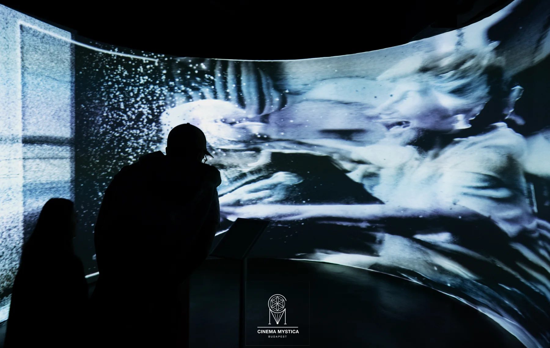 A visitor stands before a curved immersive image