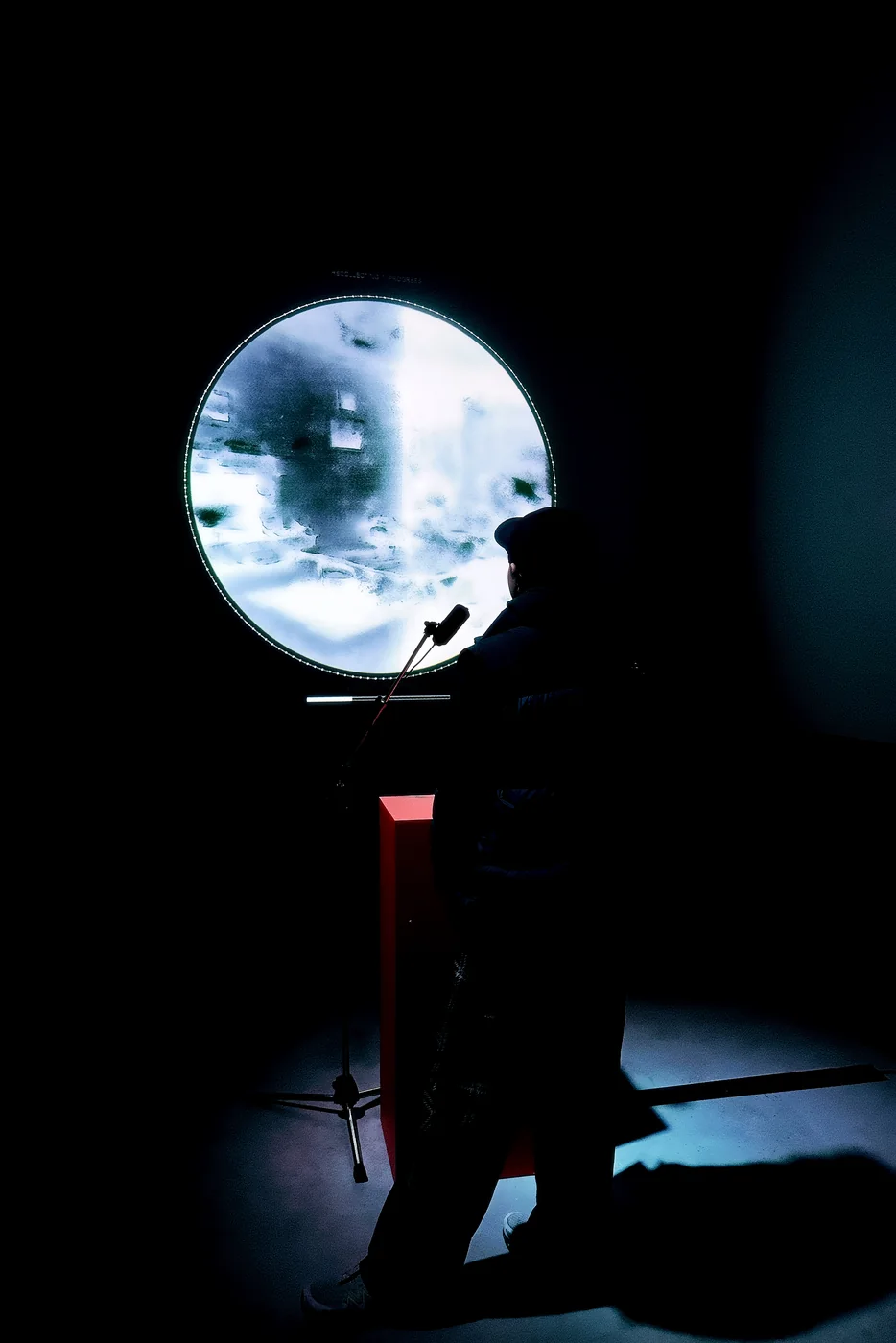 A silhouette stands against the circular installation screen